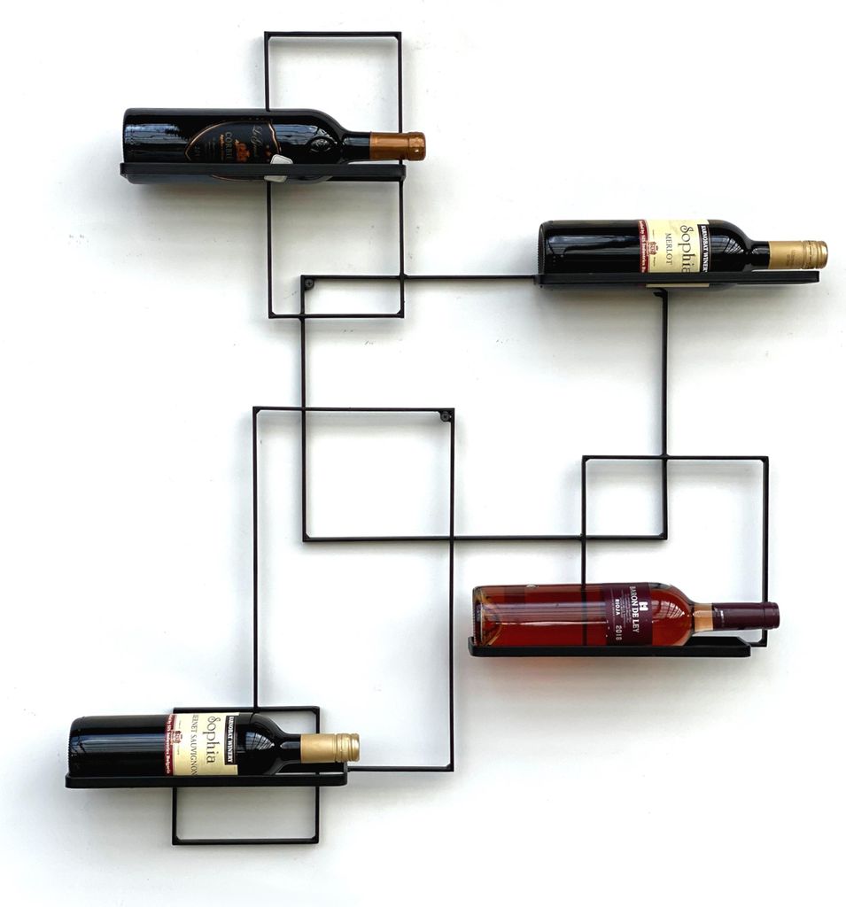 A black metal wine rack mounted on a white wall, holding four bottles of wine.