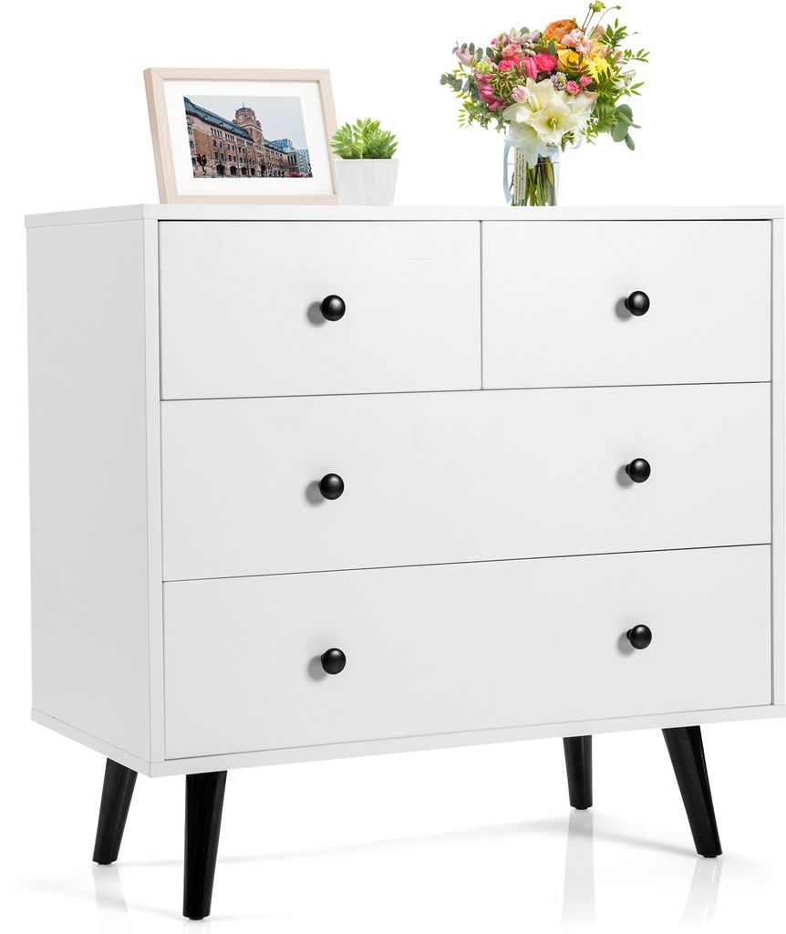 A white dresser with black legs and black knobs, decorated with a framed picture and a bouquet of flowers.