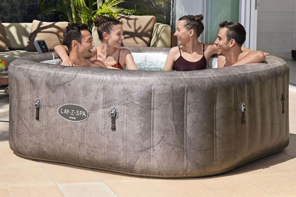 Four people are enjoying themselves in an inflatable hot tub outdoors.