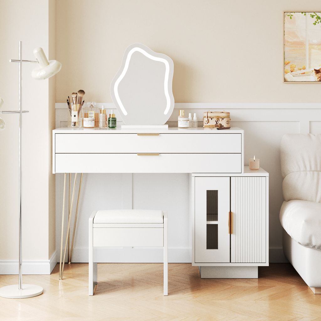A white vanity table with a mirror, stool, and side cabinet in a bedroom setting.
