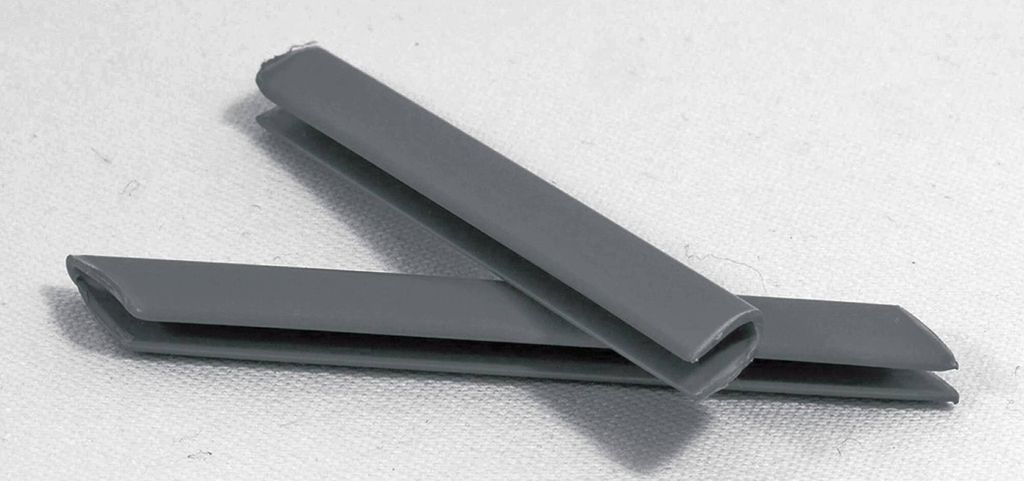 Two gray plastic profile connectors are placed on a white surface.