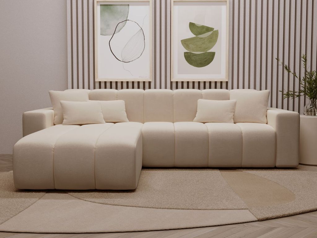 A modern beige sectional sofa with an ottoman in a living room setting, with abstract art on the wall.
