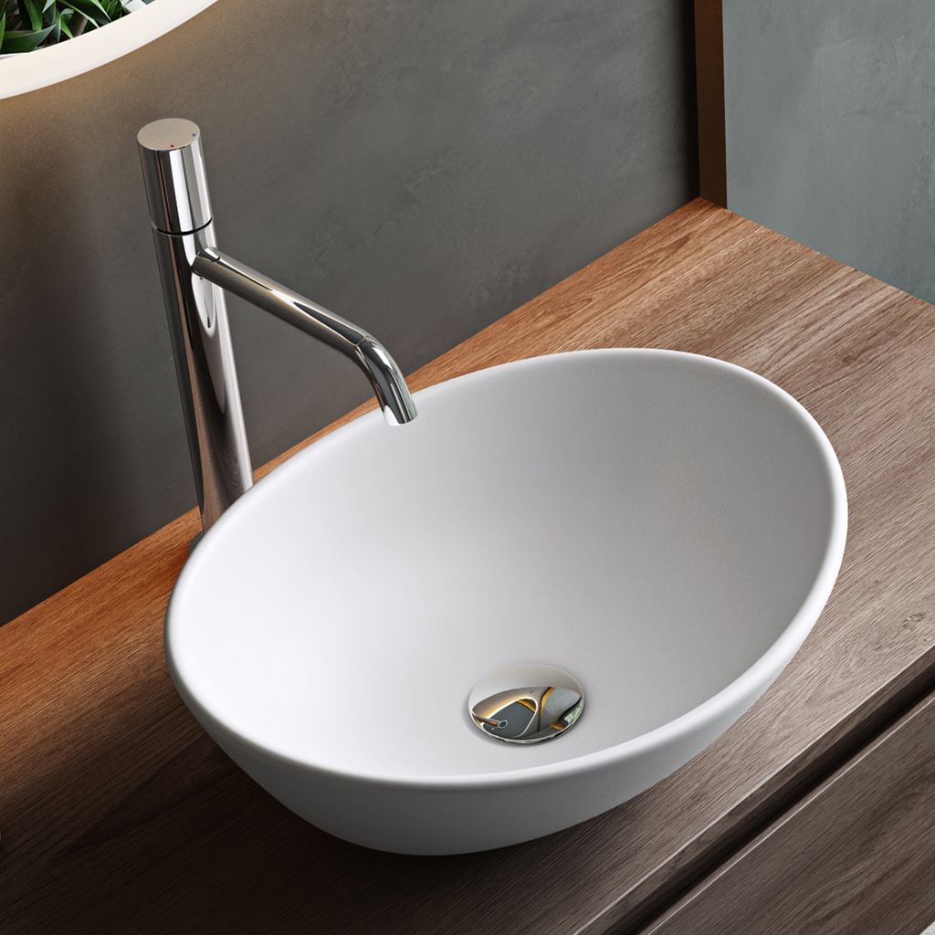 A white ceramic vessel sink with a chrome faucet on a wooden countertop.