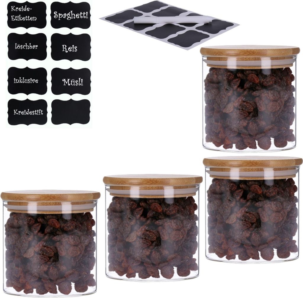 Four glass jars filled with raisins, each with a bamboo lid, are arranged on a white background. A set of black chalkboard-style labels is also visible in the upper left corner.