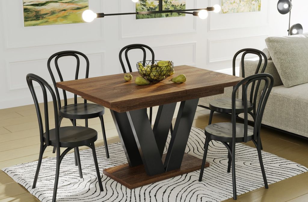 A dining table with chairs and a bowl of fruit on it, set in a dining room with a sofa in the background.