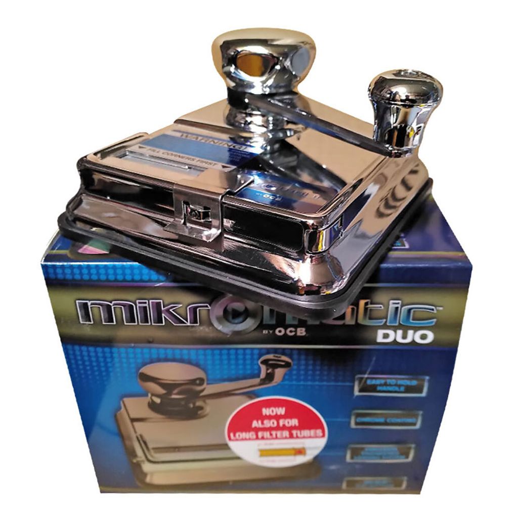 A chrome cigarette rolling machine sits on top of its product packaging.