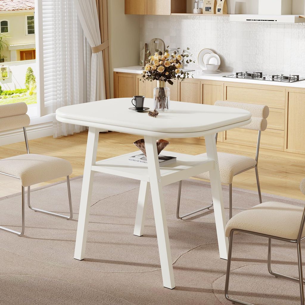 A white dining table with a shelf underneath, set in a modern kitchen/dining area with chairs and a vase of flowers on the table.