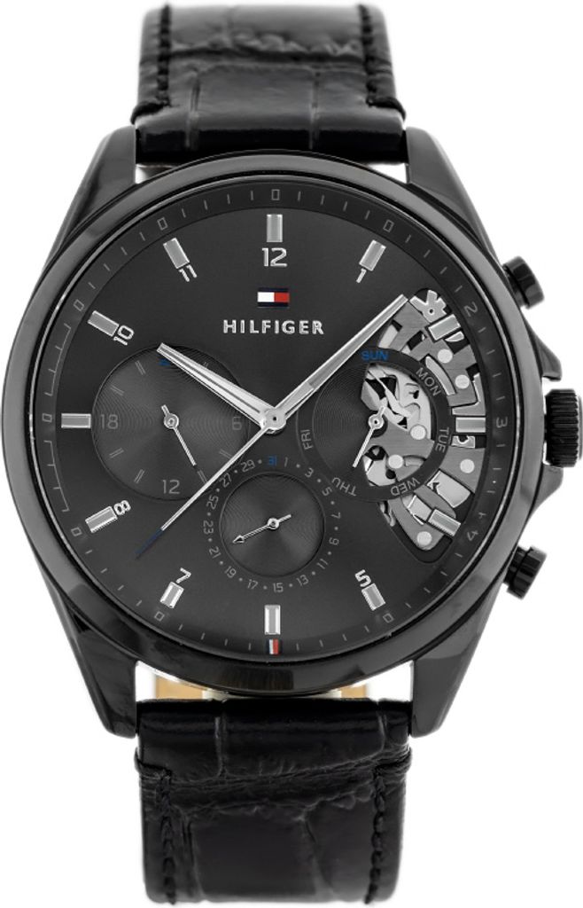 A close-up studio shot of a black Tommy Hilfiger men's watch with a black leather strap.