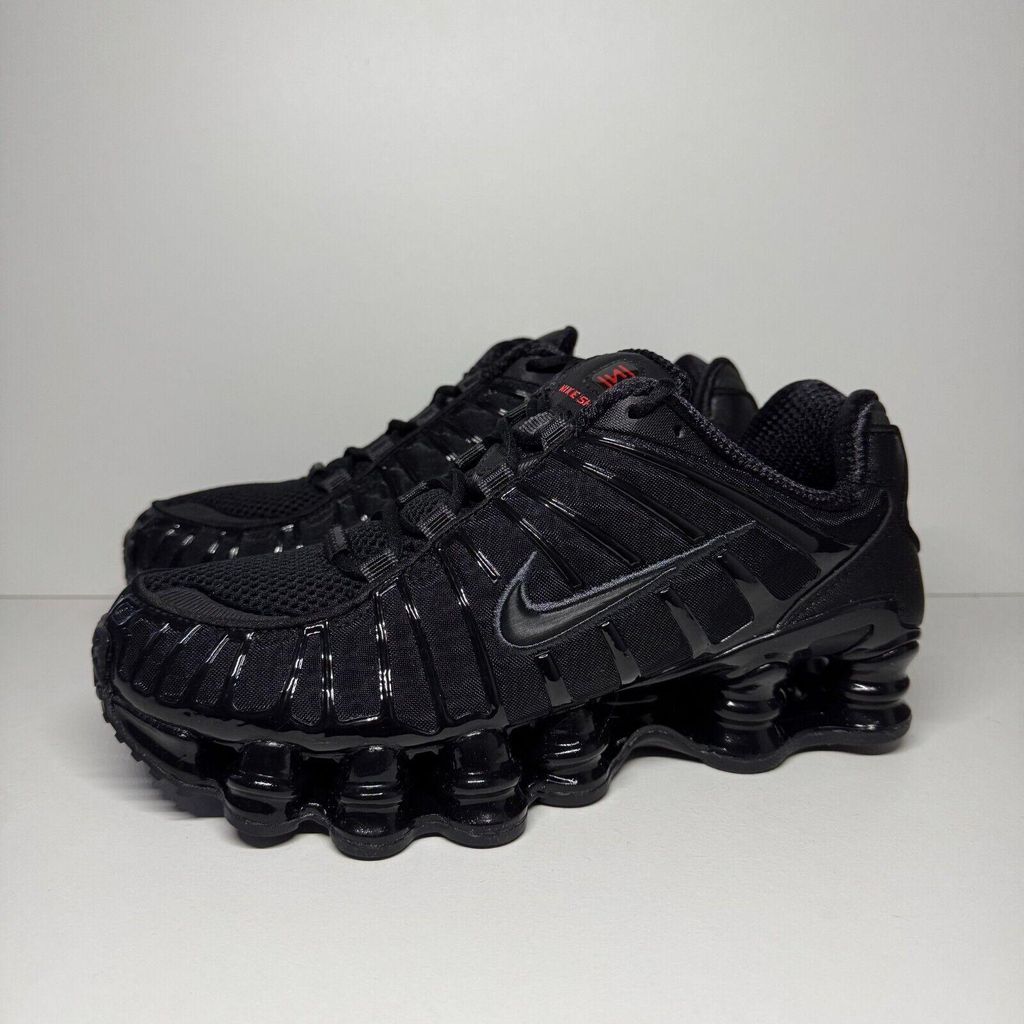A pair of black Nike Shox TL sneakers are displayed against a plain light gray background.