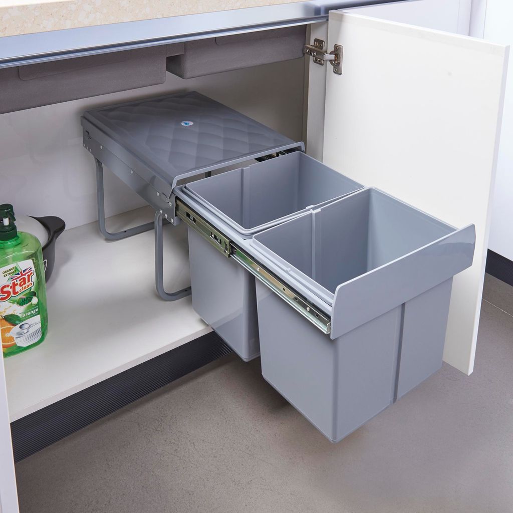 A built-in trash can with two compartments is pulled out from under a kitchen counter.