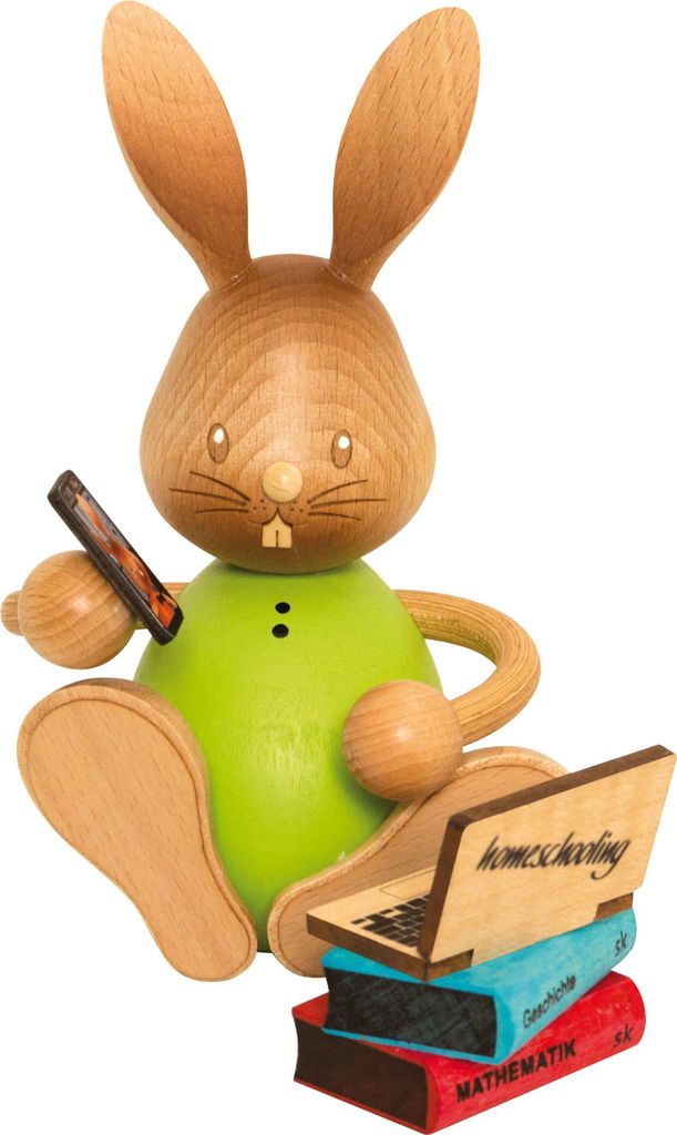 A wooden figurine of a rabbit sitting with a laptop and books.
