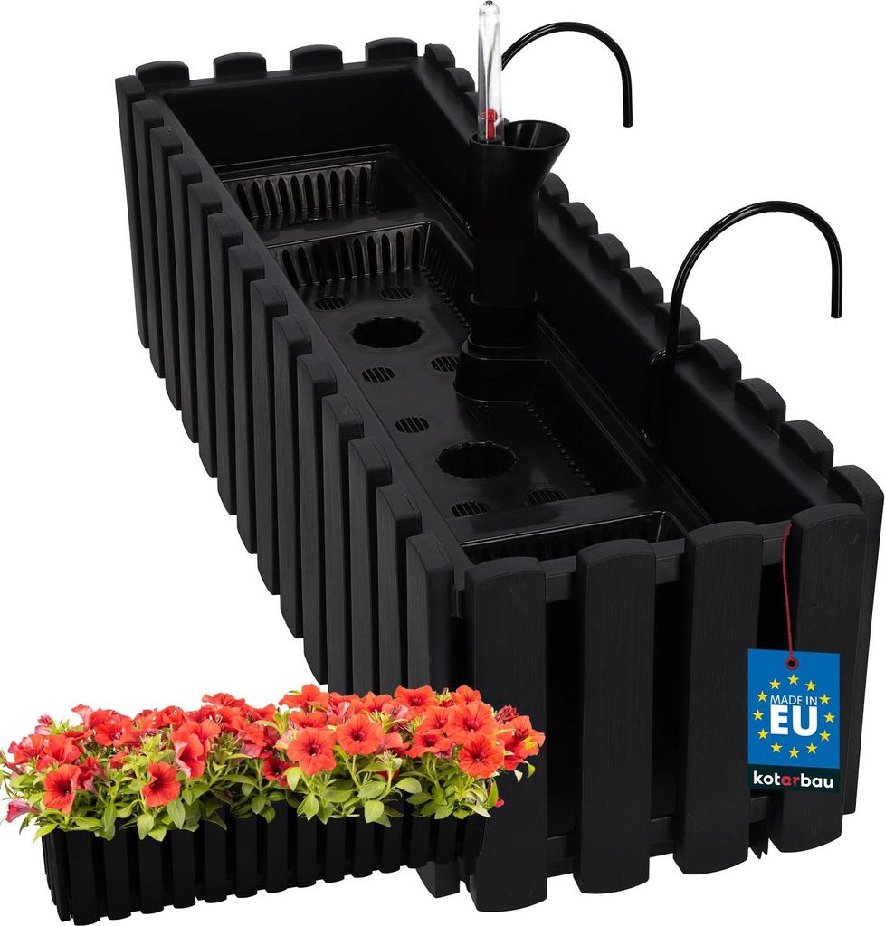 A black plastic planter box with a self-watering system and a small tray of red flowers in front of it.