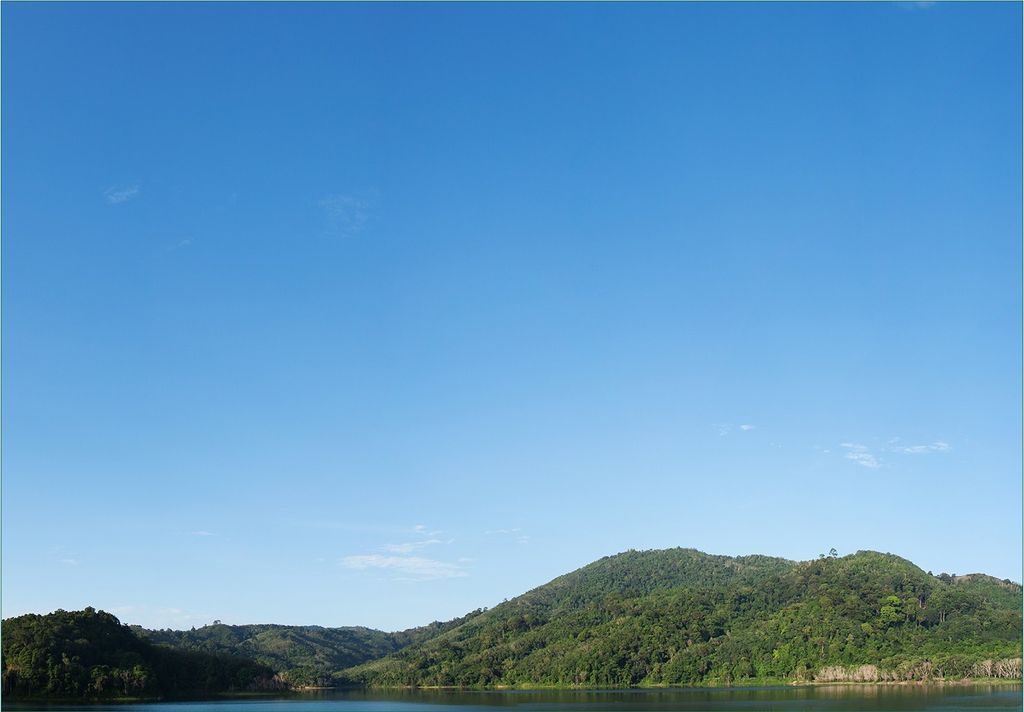 Wallario Fototapete Vliestapete, seidenmatte Oberfläche, einfache Verarbeitung, Größe 200 x 140 cm, Motiv Grüne Hügel am Wasser