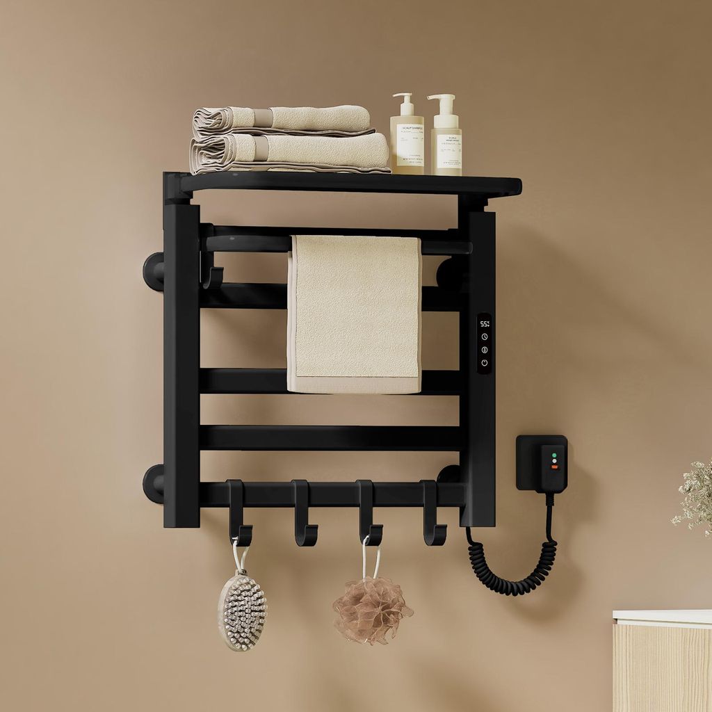 A black electric towel warmer mounted on a light brown wall, with towels, soap dispensers, and bath accessories displayed.