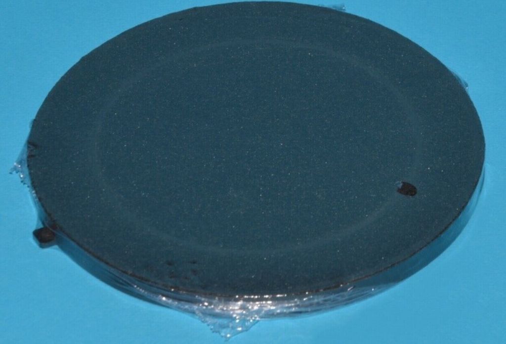 A dark circular object covered in plastic wrap, resting on a light blue surface.