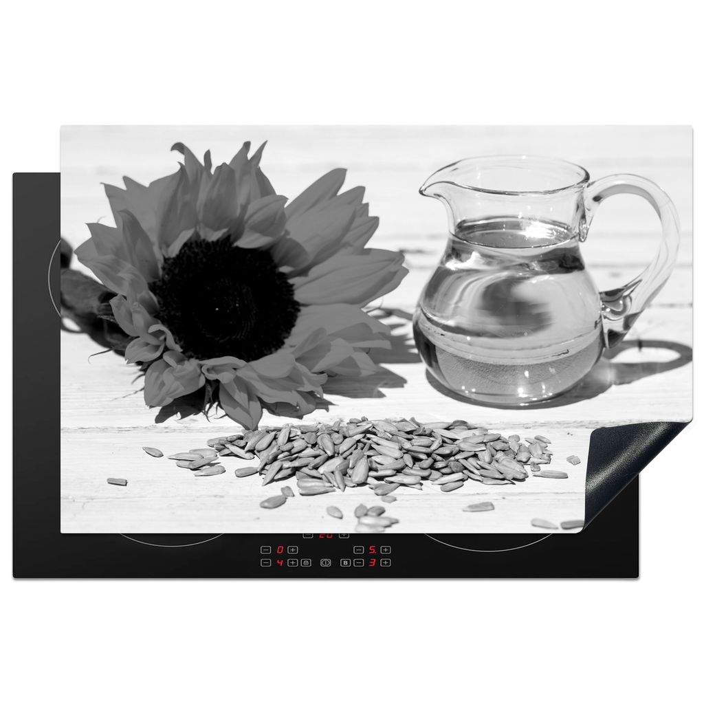 KitchenYeah Herdabdeckplatte Sonnenblumenkerne mit Sonnenblumenöl in einem kleinen Glas und Sonnenblume auf einem weißen Tisch - schwarz und we...