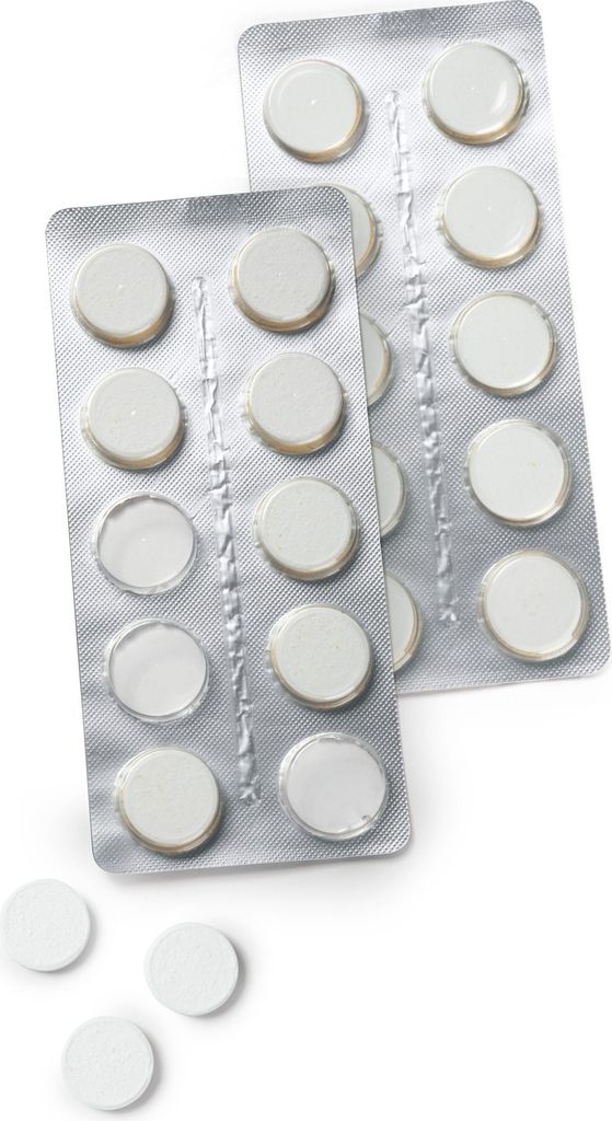 Two blister packs of white tablets and four loose white tablets on a white background.