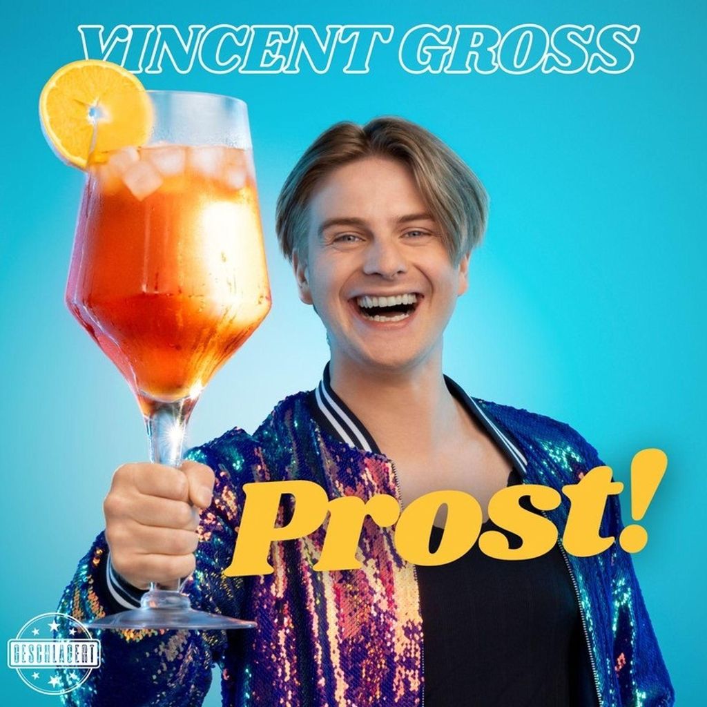 A man holds up a drink and smiles.