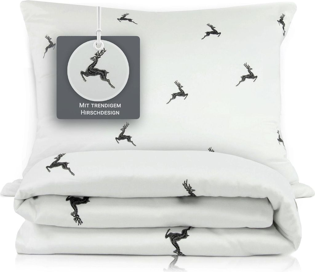 A white pillow and folded duvet cover with a repeating pattern of black deer silhouettes, presented on a white background.