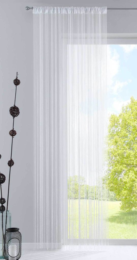 A white sheer curtain hangs in front of a window with a view of trees and sky.
