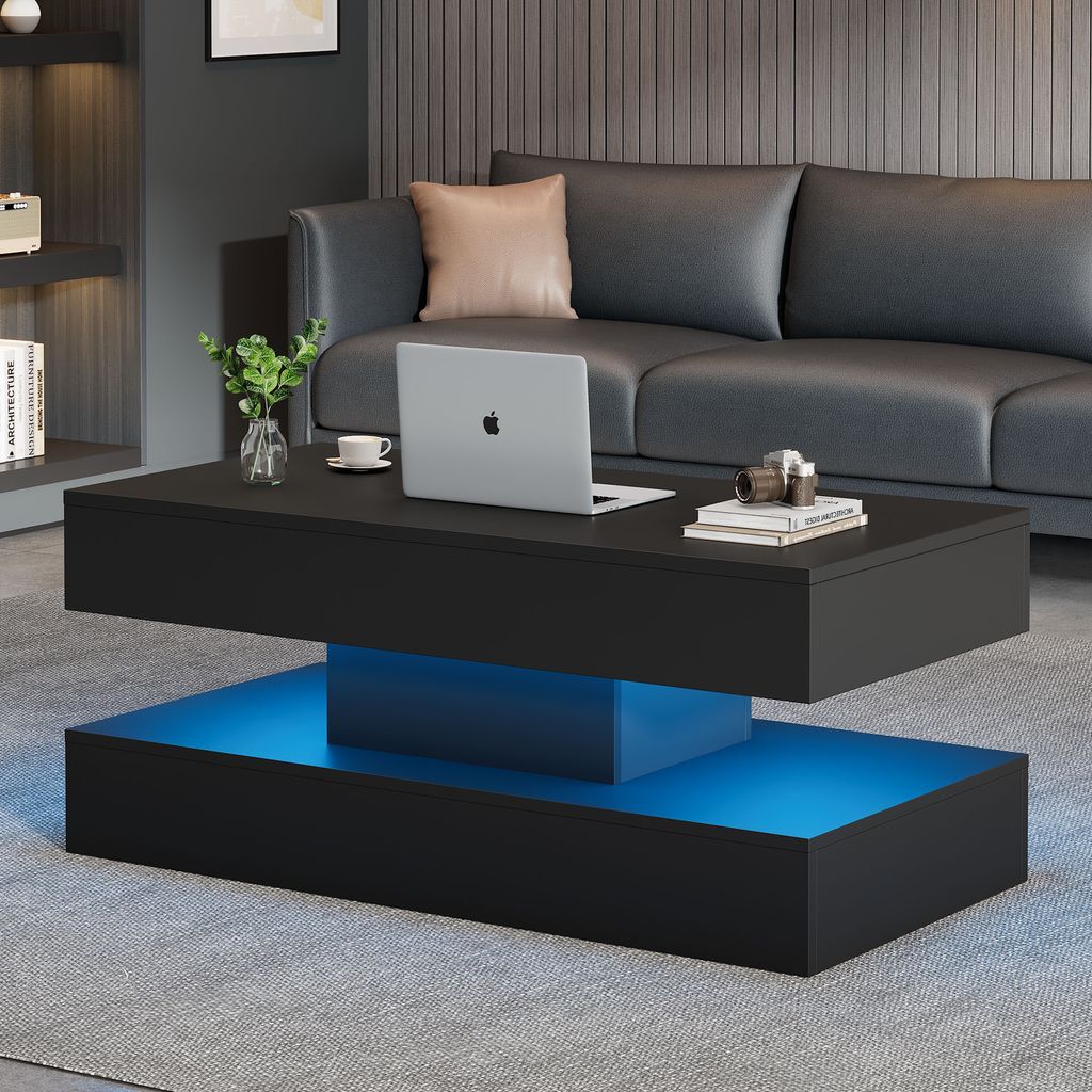 A modern living room with a black coffee table featuring LED lighting, a laptop, and a vase of plants.