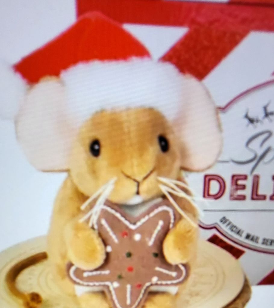 A plush toy mouse wearing a Santa hat and holding a gingerbread cookie.
