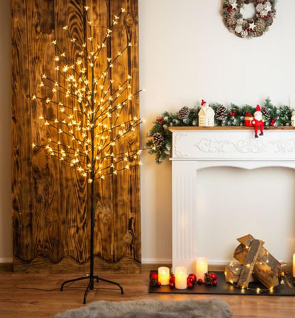 A decorative LED tree is placed next to a fireplace decorated for Christmas.