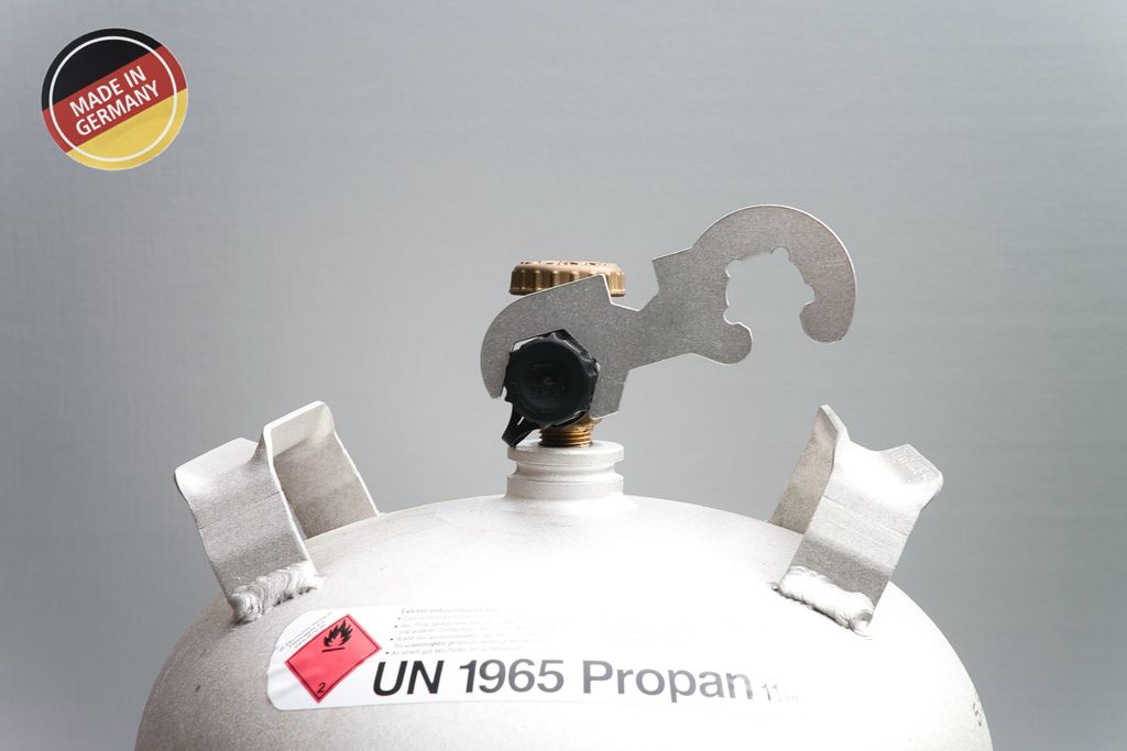 Close-up of the top of a white gas cylinder with a metal tool attached to the valve.