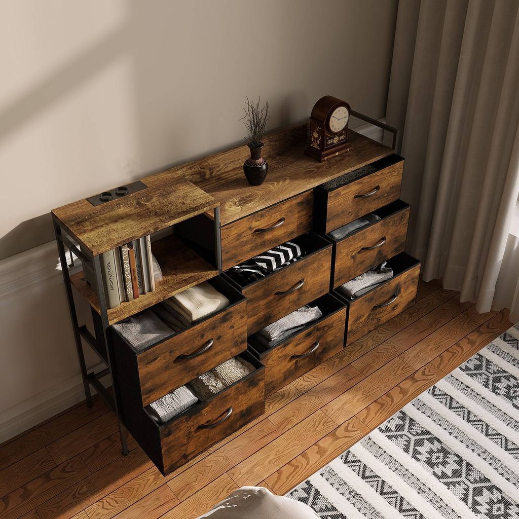 A dresser with multiple drawers and a shelf unit on the left, all in a vintage wood finish, placed on a wooden floor next to a rug.