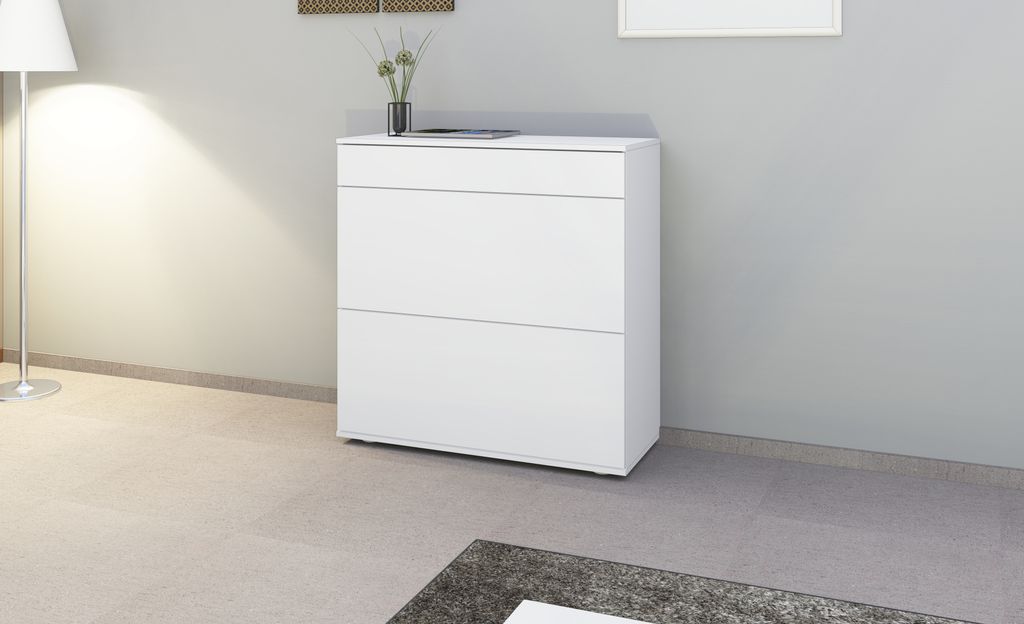 A white shoe cabinet is shown in a room with a floor lamp and a grey wall.