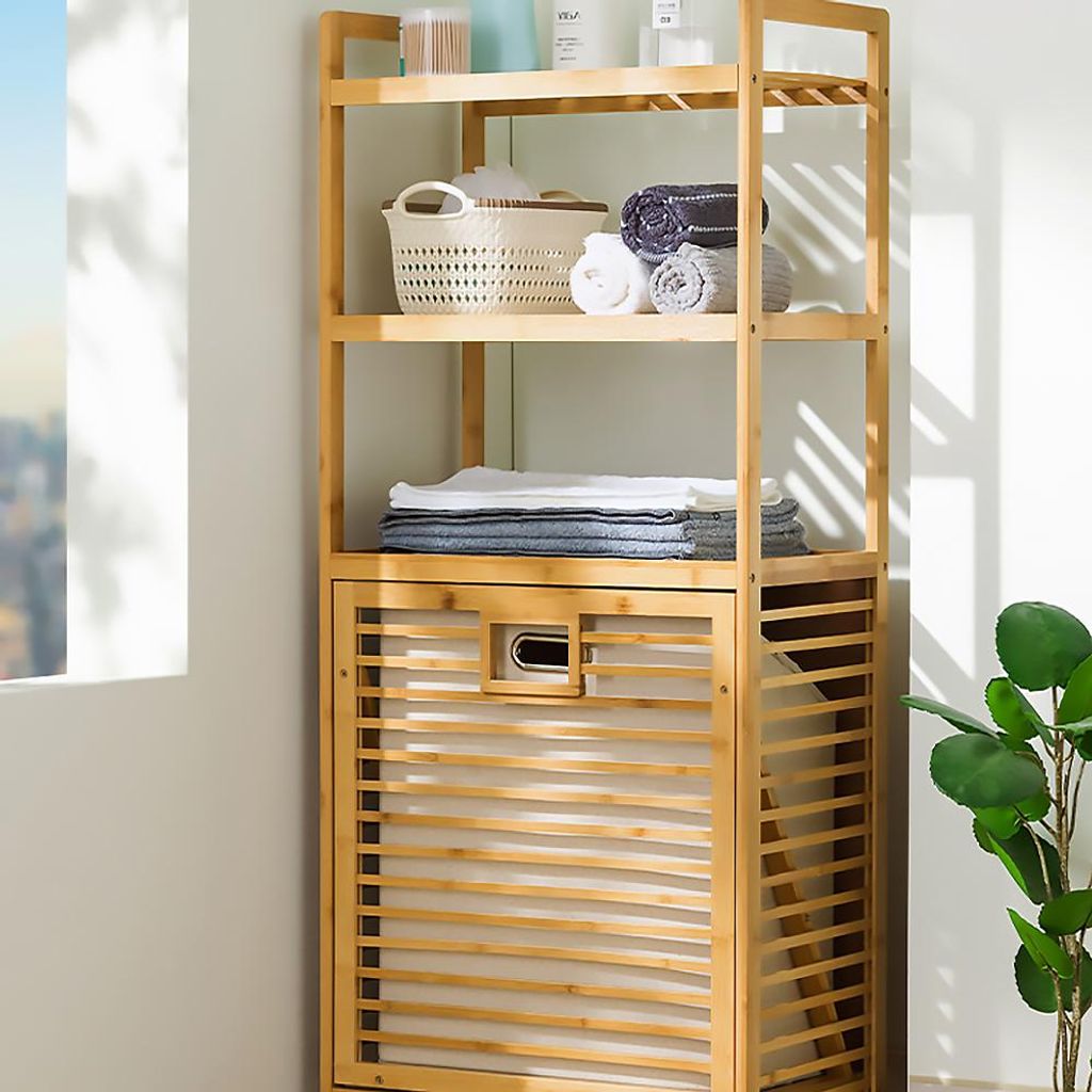 A bamboo shelving unit with a laundry basket, holding folded towels and toiletries.