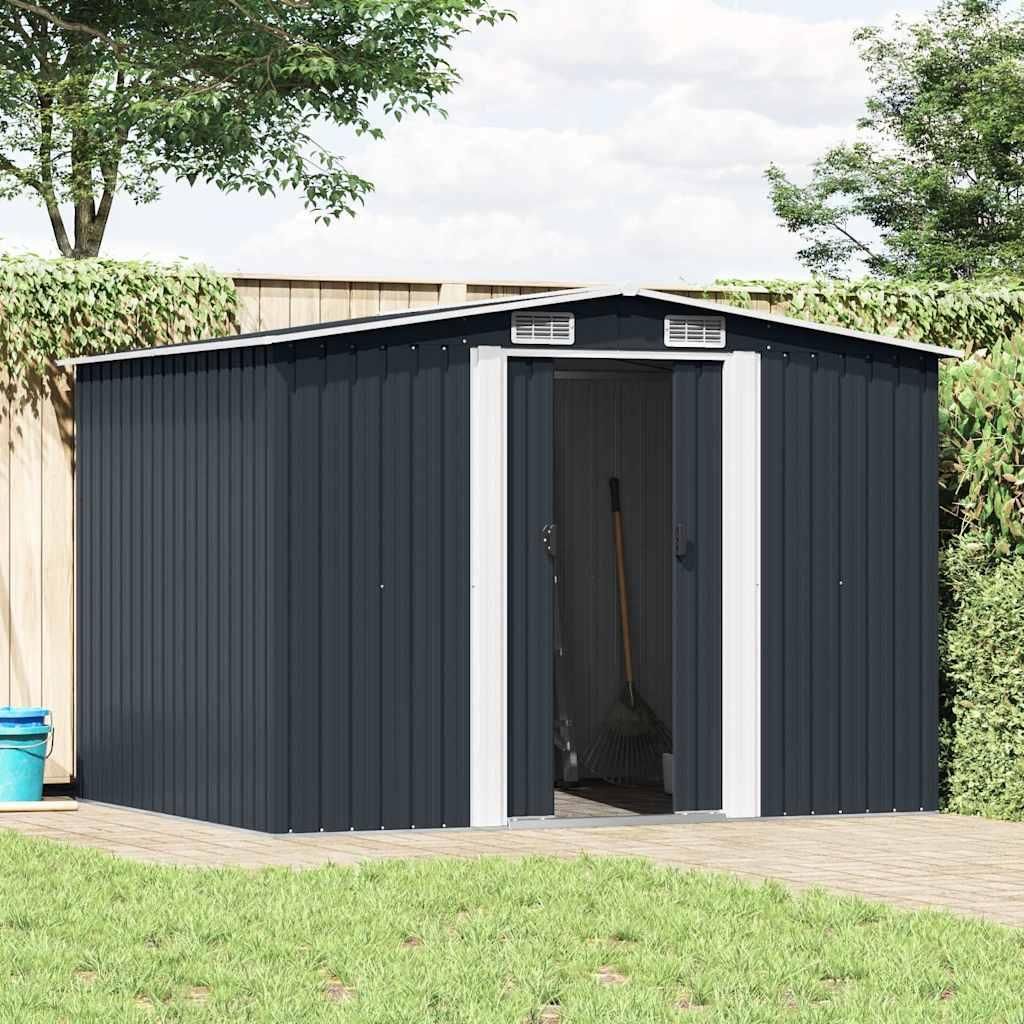 A dark gray metal garden shed with double doors is shown in an outdoor setting with a wooden deck and green grass.
