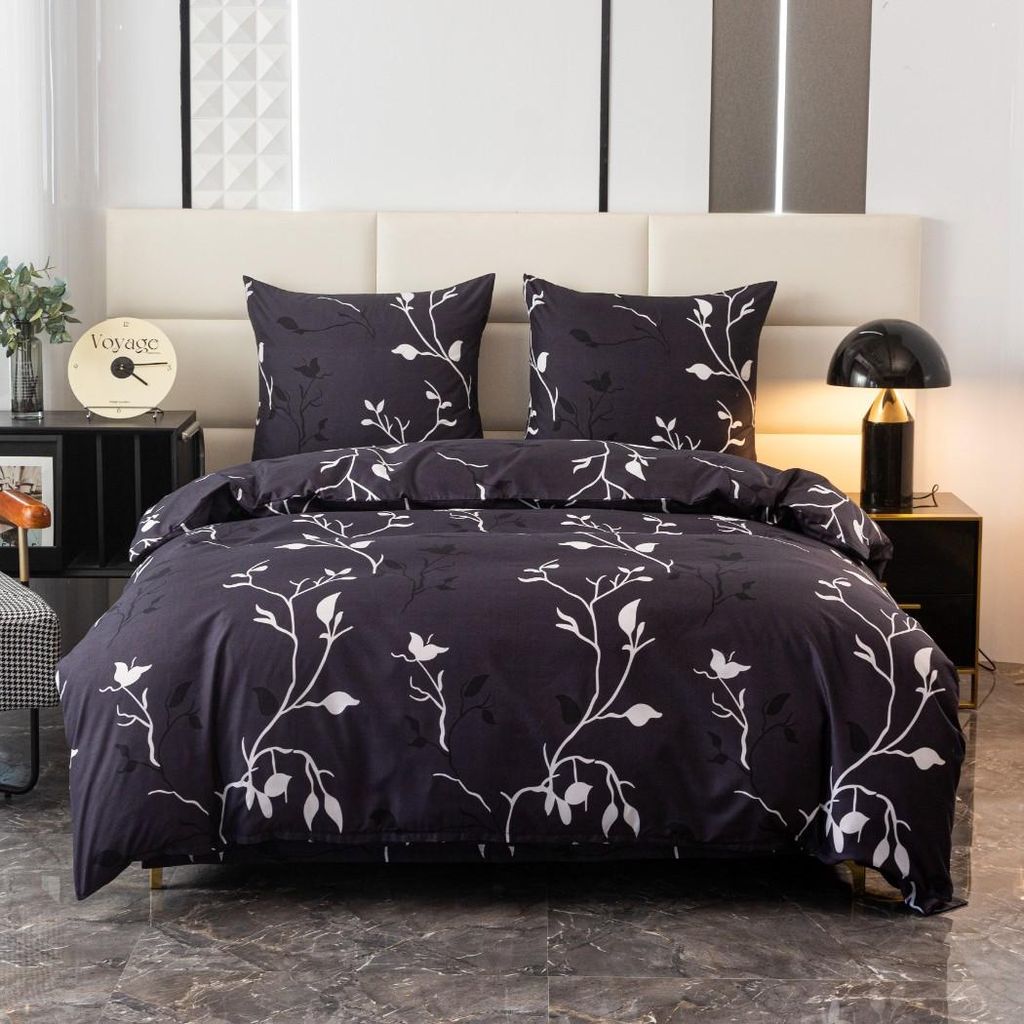 A neatly made bed with a dark duvet cover and pillowcases featuring a white leaf pattern.