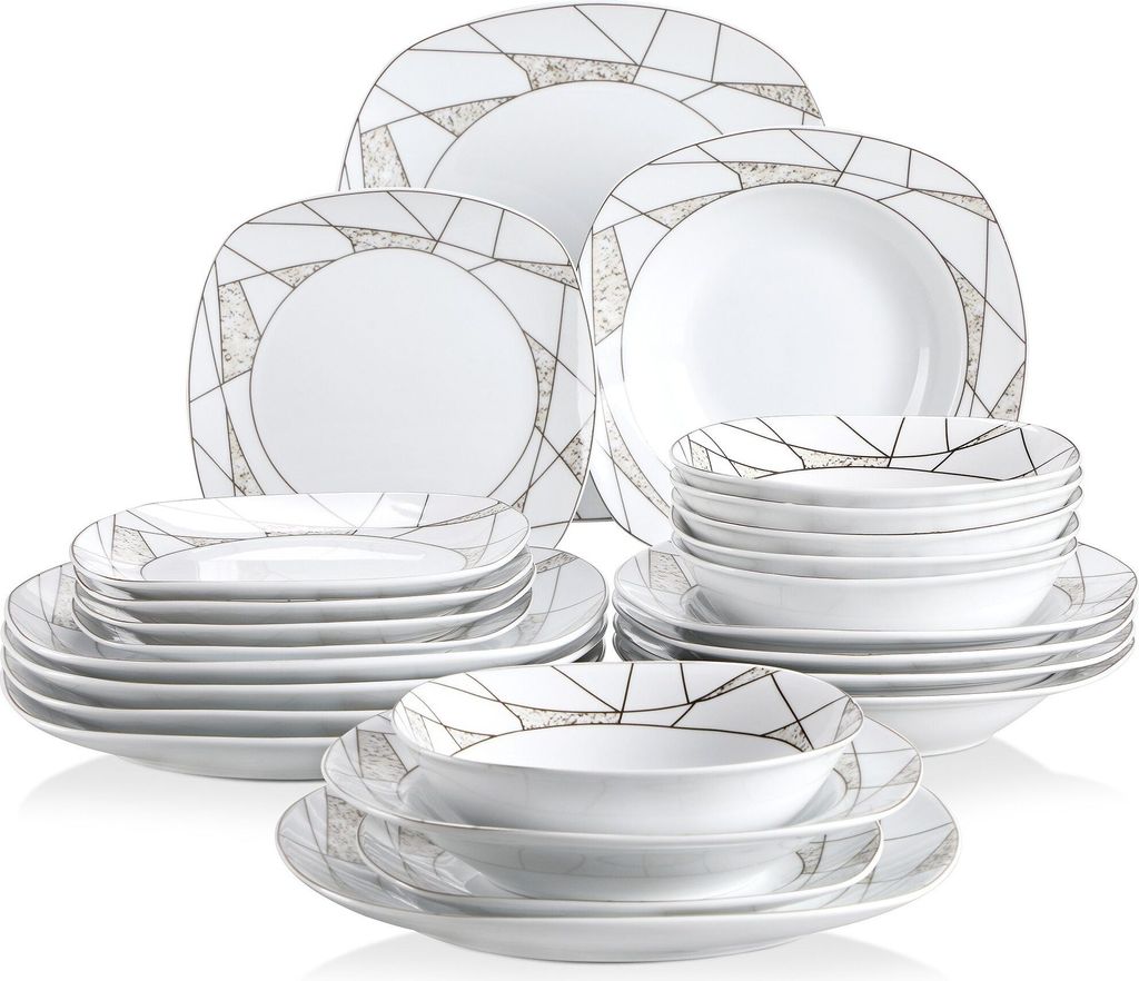 A collection of white dinnerware with a geometric gold and gray pattern, stacked and arranged.
