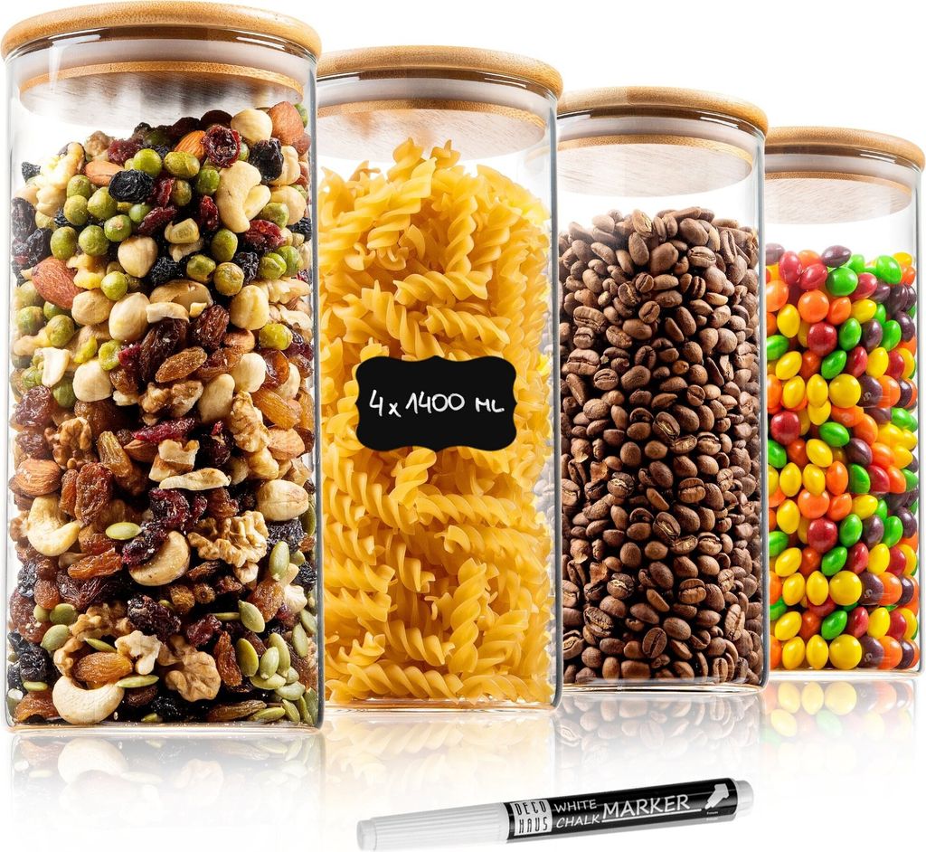 Four glass storage jars filled with different food items, placed on a white surface with a marker pen in the foreground.