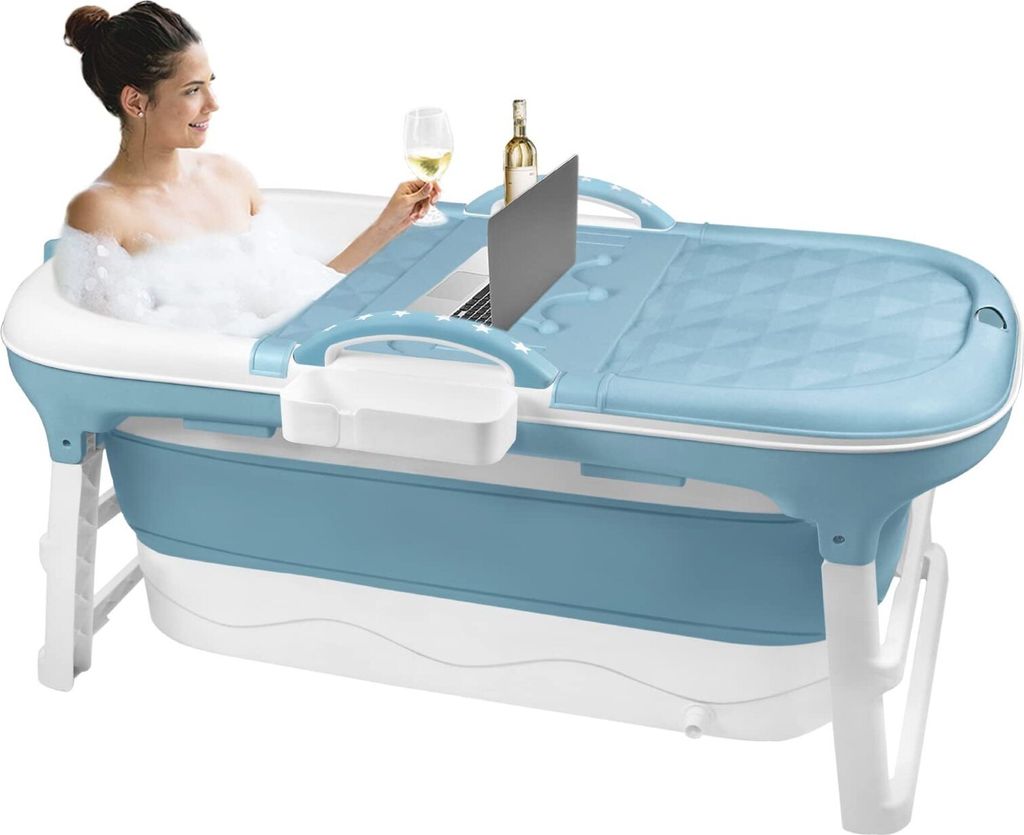 A woman is relaxing in a portable bathtub with a laptop, a glass of wine, and a bottle of wine on a tray attached to the tub.