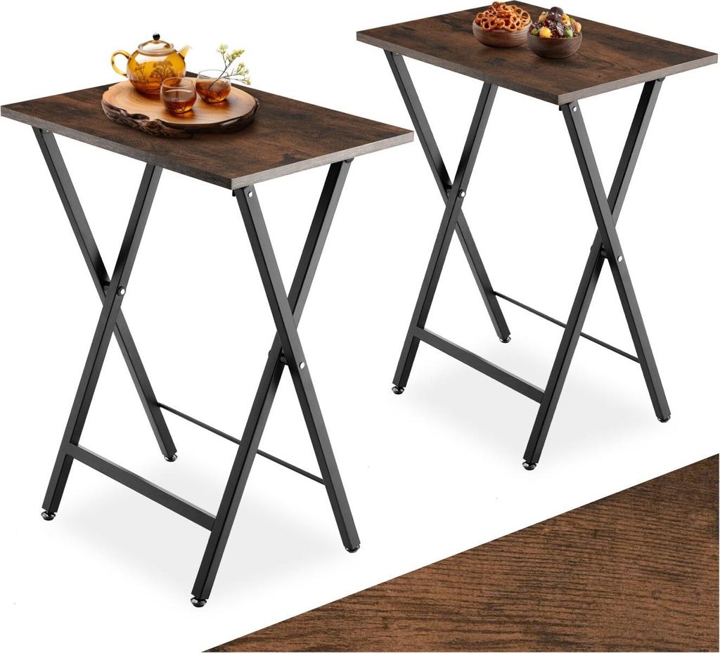 Two folding side tables with dark wood-effect tops and black metal frames, set against a white background. One table has a teapot and two small cups on it, while the other has two bowls of snacks.