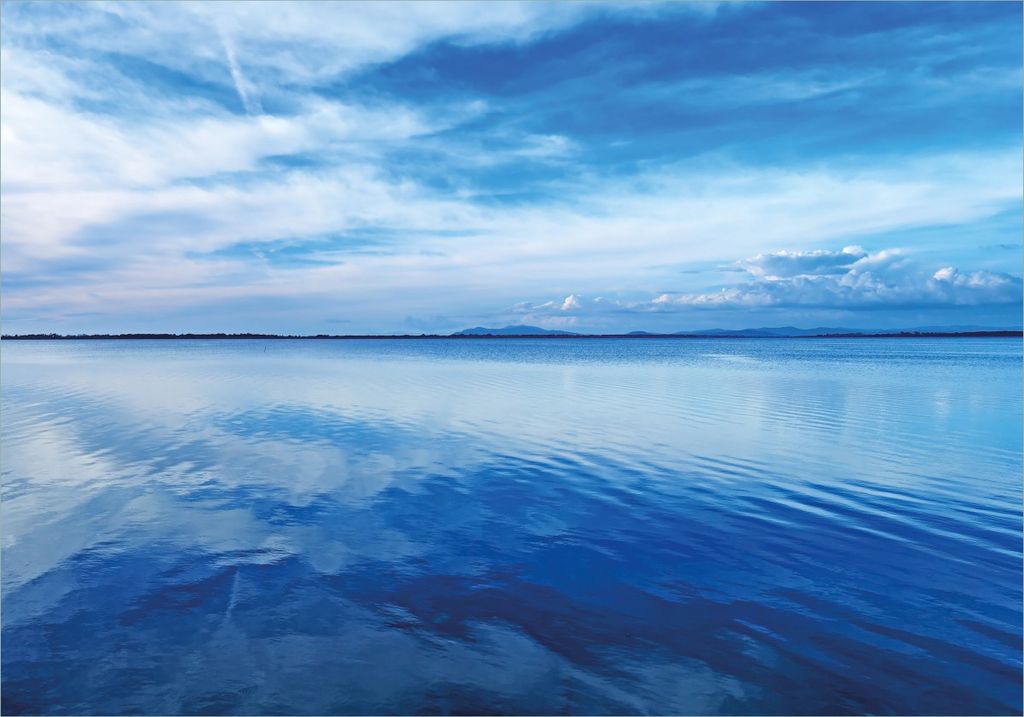 Wallario selbstklebendes Poster - Blaue Meeresbucht in Italien mit Spiegelung im Wasser, Größe: 70 x 100 cm