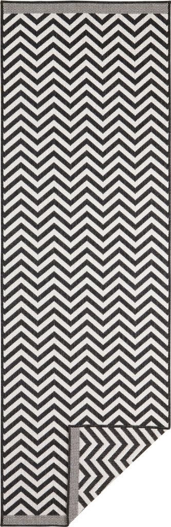 A black and white chevron patterned rug, with a corner folded back.