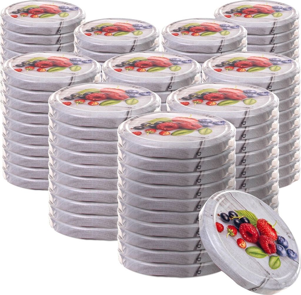 A stack of round metal lids with fruit designs, with one lid in the foreground.