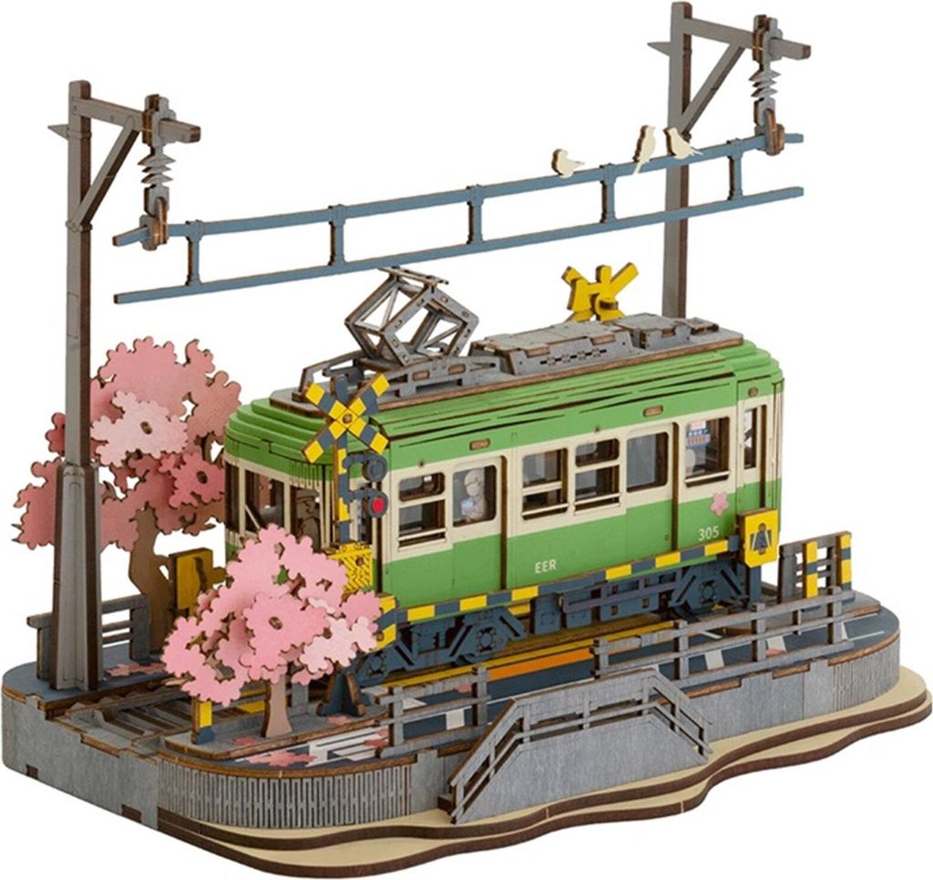 A 3D wooden model of a train station with a green train, cherry blossom trees, and overhead power lines.
