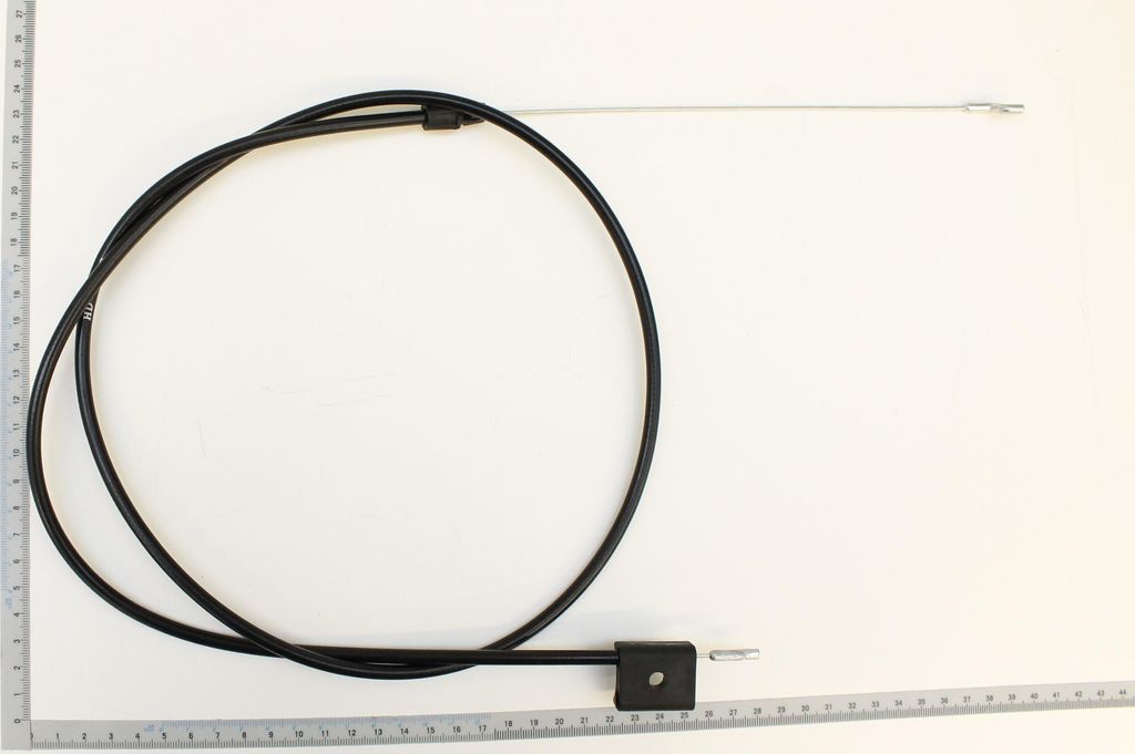 A black Bowden cable with a silver metal end is laid out on a white surface next to a ruler.