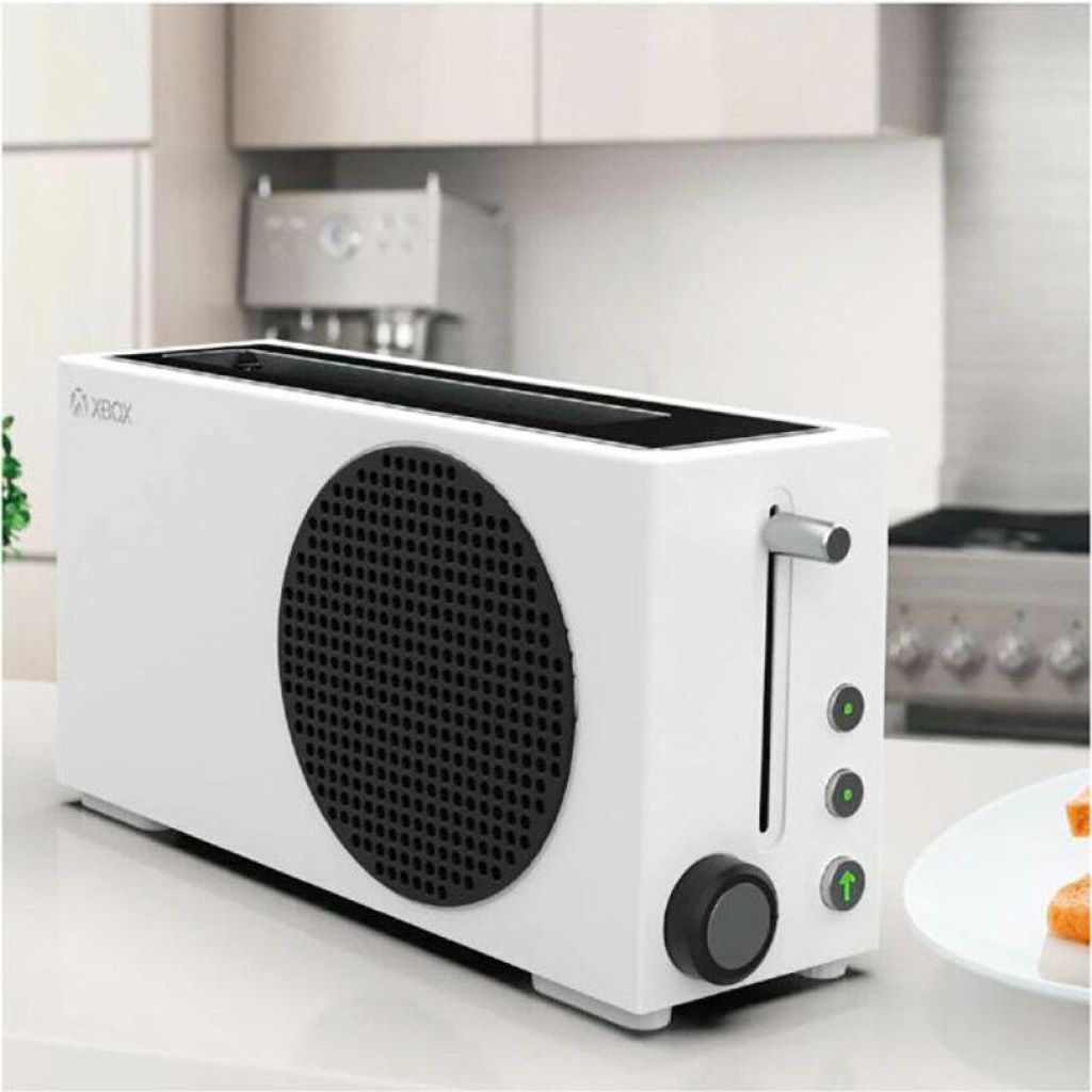 A white toaster with a black circular grill on the side, resembling an Xbox Series S console, sits on a kitchen counter.