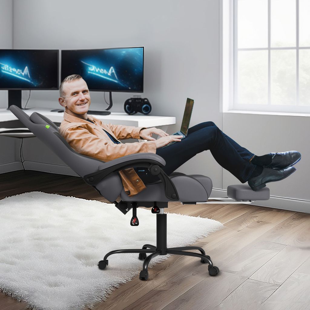 A man is sitting in a gaming chair with a laptop on his lap, in a home office setting.