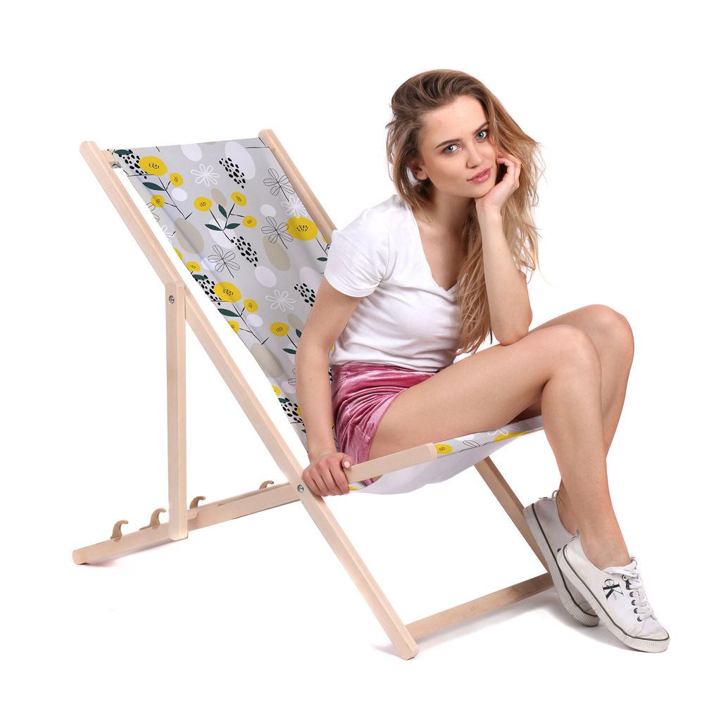 A woman is sitting on a foldable deck chair with a floral pattern.