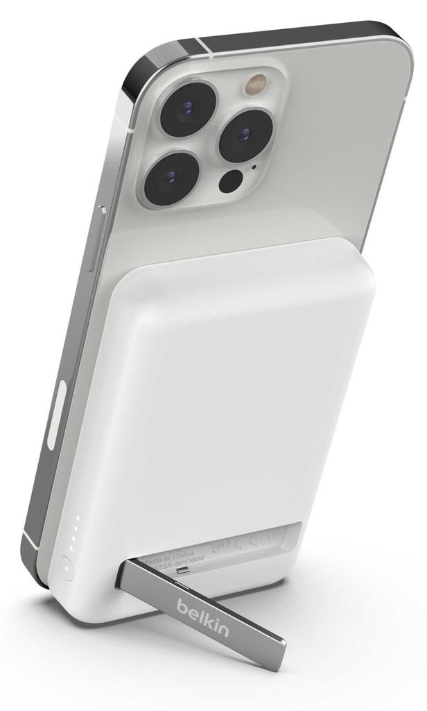 A white Belkin power bank is attached to the back of a silver smartphone, with a kickstand extended.