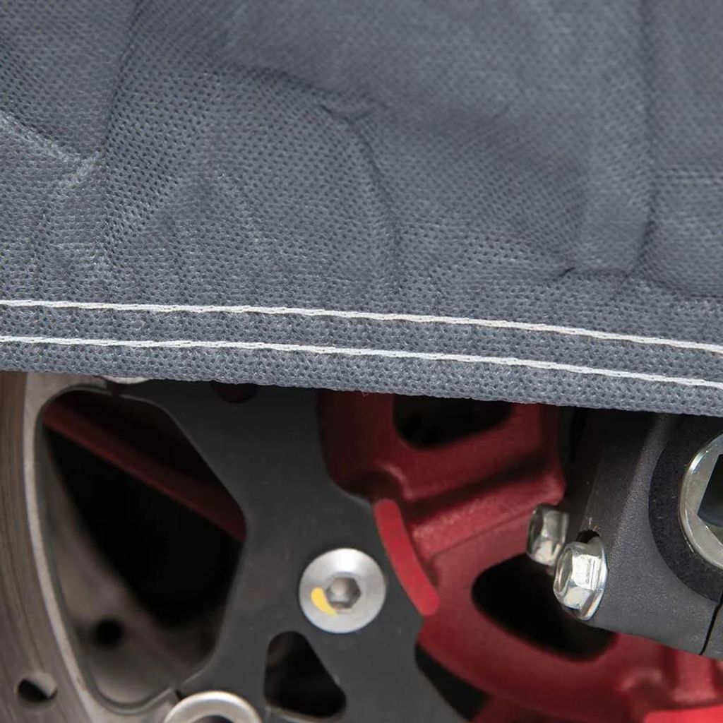 A close-up view of a motorcycle brake disc and caliper, partially covered by a gray fabric cover.