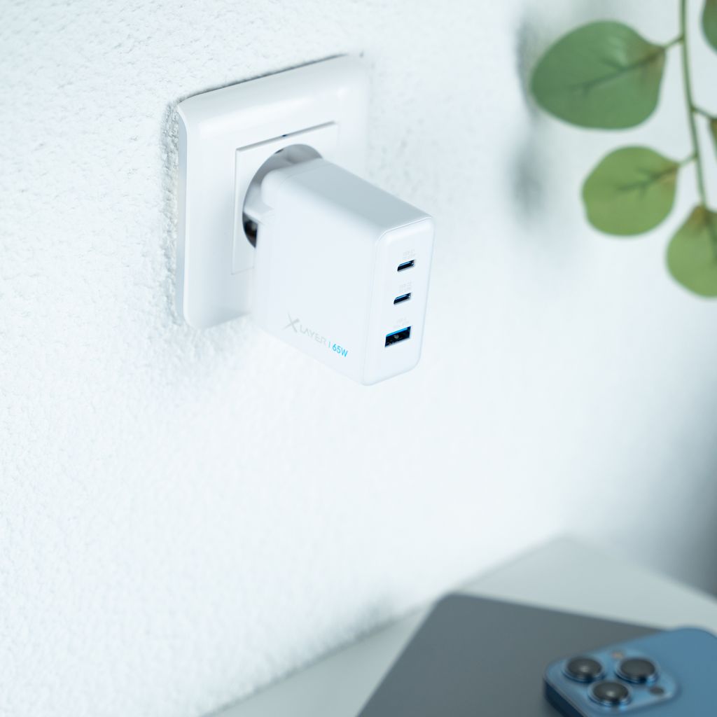 A white USB-C charger plugged into a white wall socket.