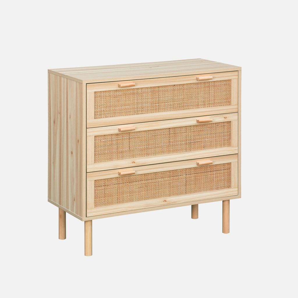 A three-drawer dresser with rattan drawer fronts and wooden legs, set against a plain light gray background.