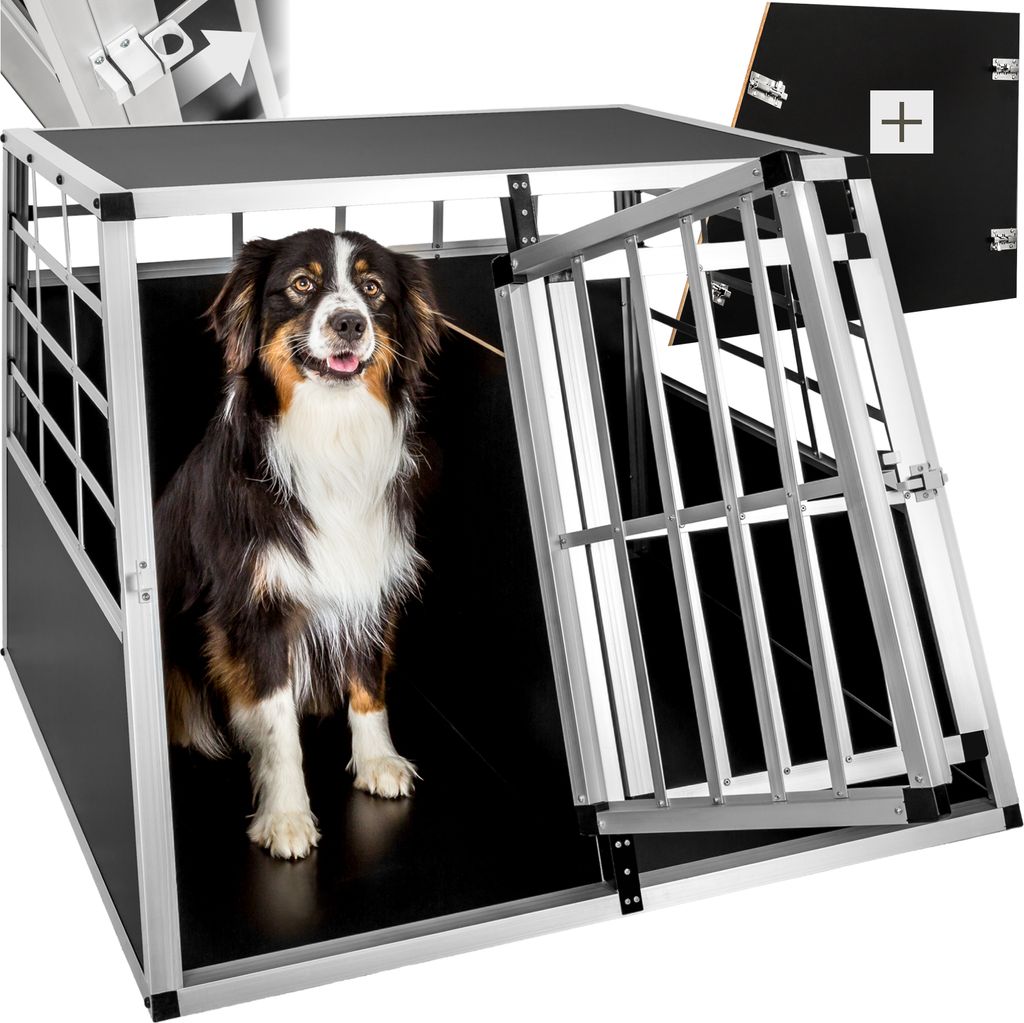 A dog is sitting inside a metal dog crate with the door open.